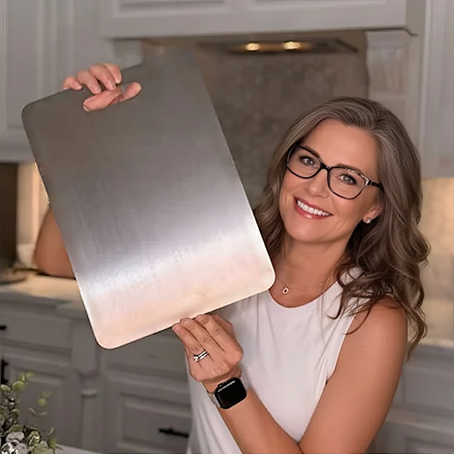Woman holding a large titanium cutting board in a kitchen
