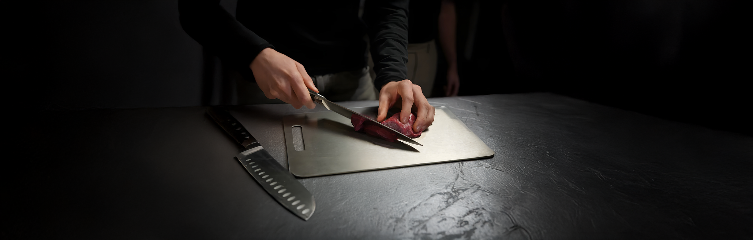 Chef cutting steak on a Titan Haus titanium cutting board