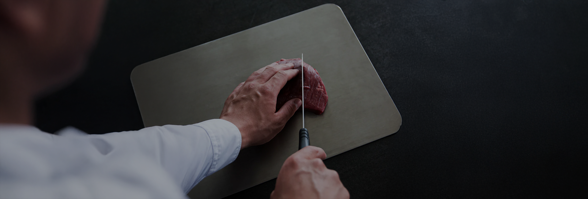Chef cutting steak on a Titan Haus pure titanium cutting board