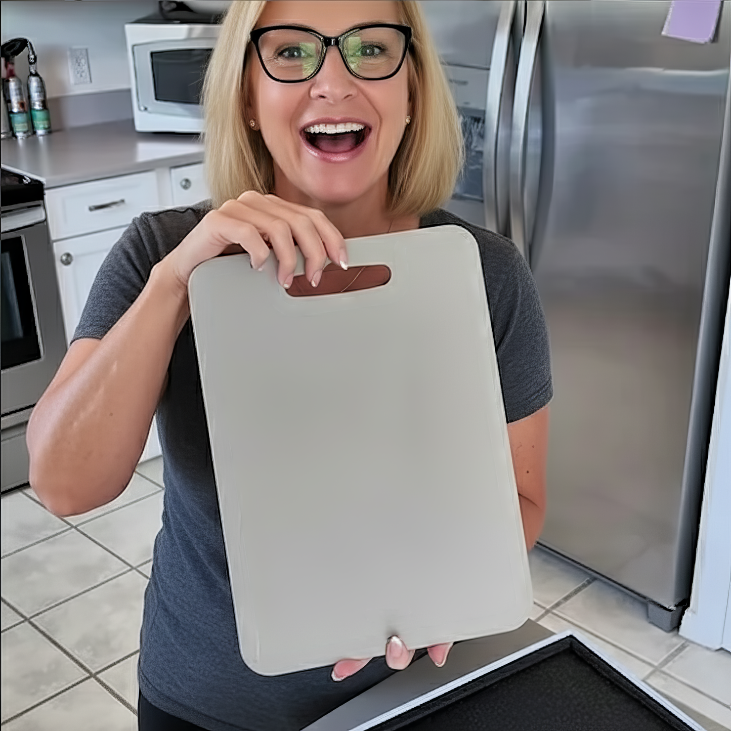 Woman holding a Titan Haus titanium cutting board in her kitchen